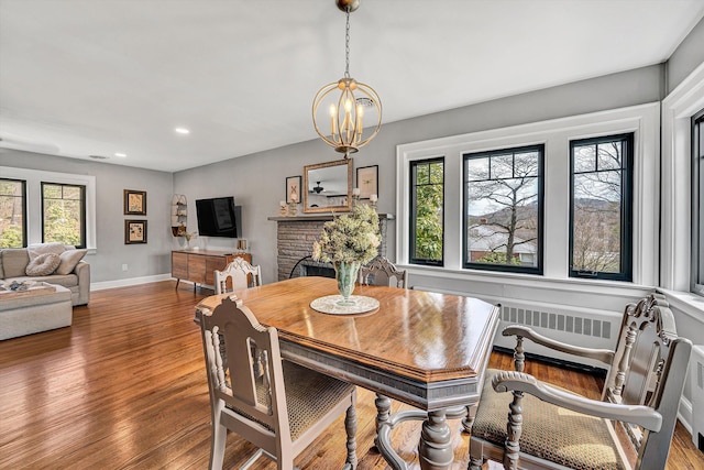 dining space with wood finished floors, baseboards, an inviting chandelier, radiator heating unit, and recessed lighting