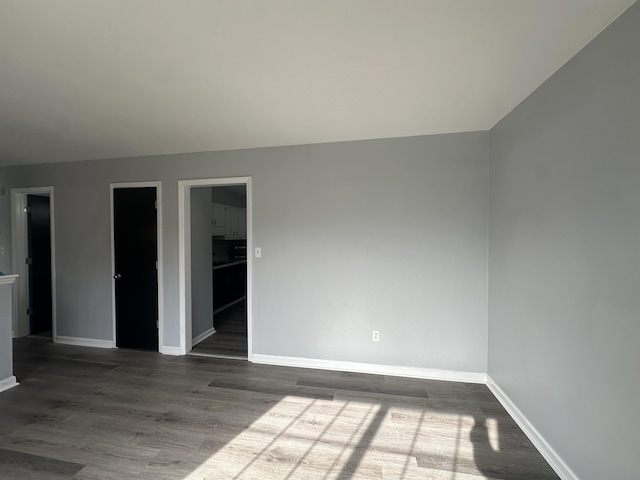 spare room featuring baseboards and dark wood-style flooring