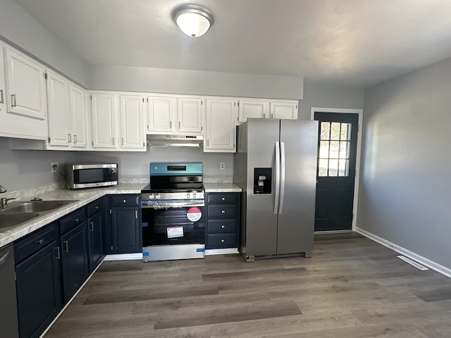 kitchen with white cabinets, under cabinet range hood, stainless steel appliances, and a sink