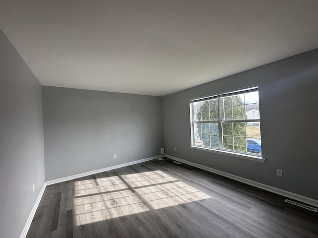 spare room with dark wood-style floors, baseboards, and visible vents