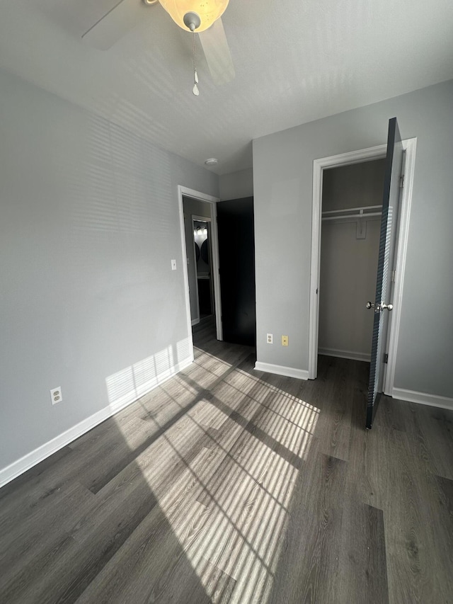 unfurnished bedroom featuring ceiling fan, a closet, baseboards, and wood finished floors