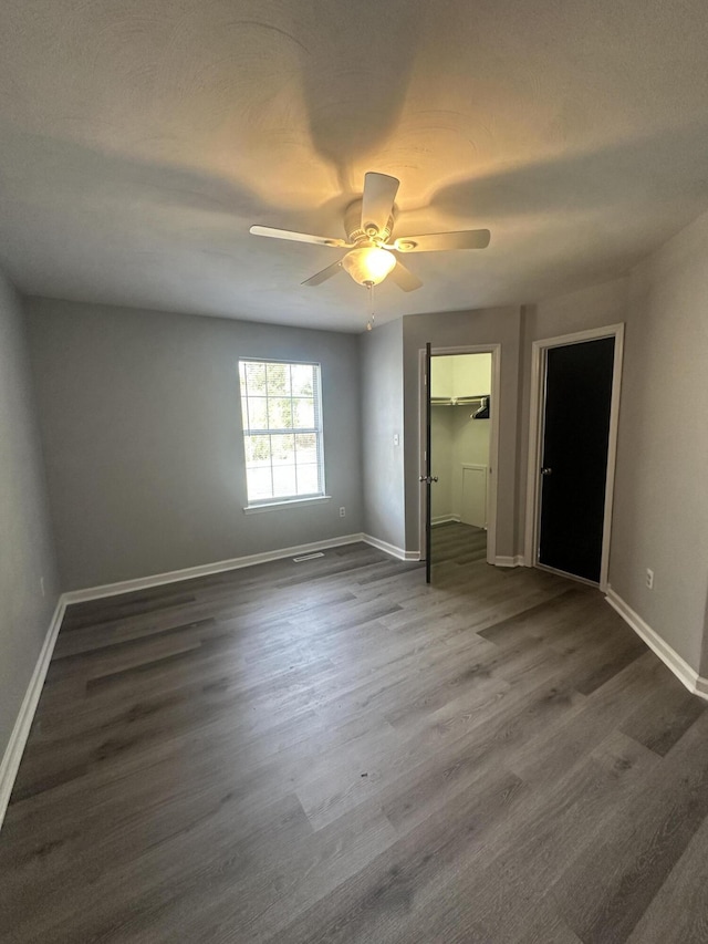 unfurnished bedroom with a closet, baseboards, dark wood finished floors, and a ceiling fan