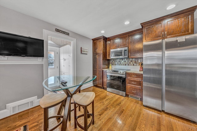 kitchen featuring appliances with stainless steel finishes, light wood-type flooring, visible vents, and tasteful backsplash