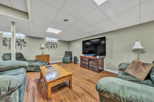 living room with a paneled ceiling, visible vents, baseboards, and wood finished floors