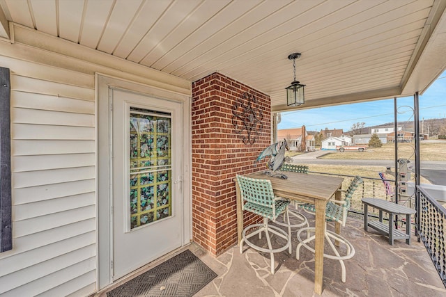 entrance to property featuring a porch and brick siding