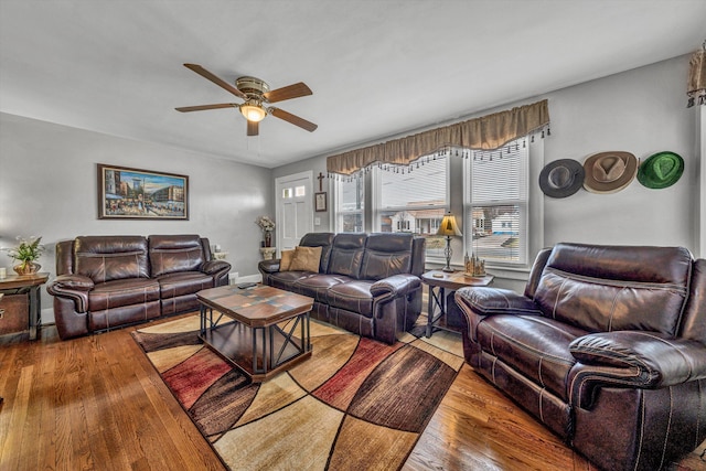 living room with wood-type flooring, a ceiling fan, and baseboards