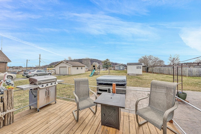 wooden deck featuring a playground, an outdoor structure, fence, and a lawn