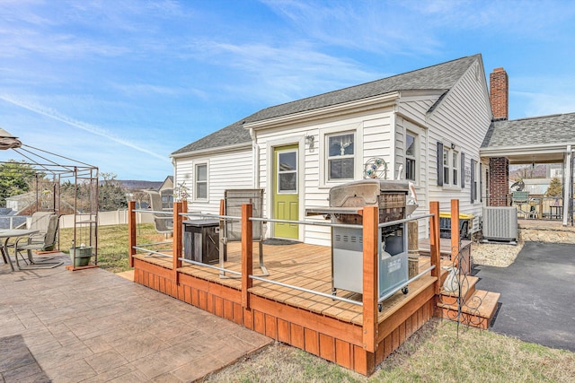 back of house with a shingled roof, a deck, and cooling unit