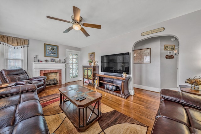 living area with a wealth of natural light, a fireplace, baseboards, and wood finished floors