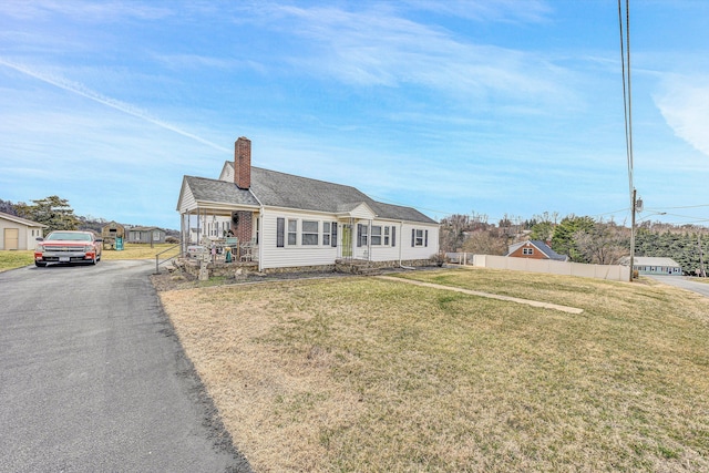 view of front facade with fence, a chimney, and a front lawn