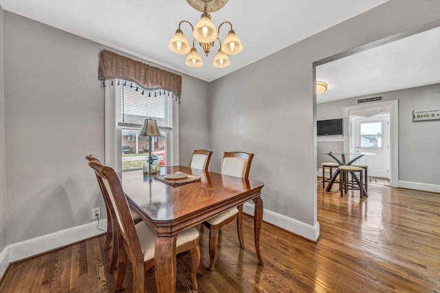 dining room featuring an inviting chandelier, baseboards, and wood finished floors