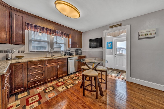 kitchen with wood finished floors, stainless steel dishwasher, plenty of natural light, and a sink