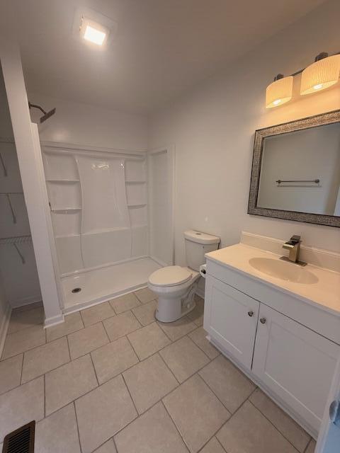 full bathroom featuring a stall shower, visible vents, toilet, tile patterned flooring, and vanity