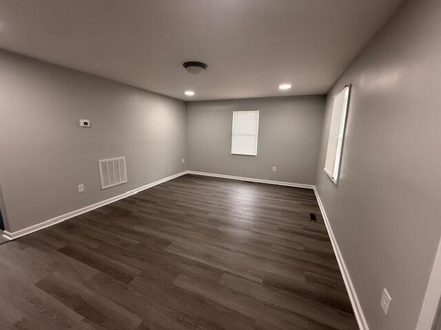 unfurnished room featuring recessed lighting, dark wood finished floors, visible vents, and baseboards