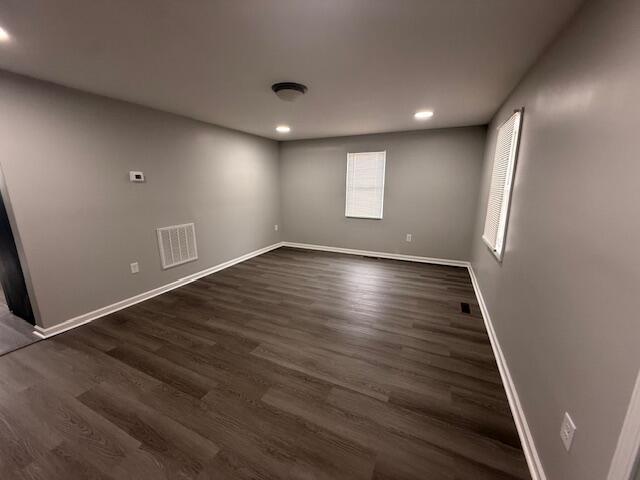 empty room with baseboards, visible vents, dark wood-type flooring, and recessed lighting