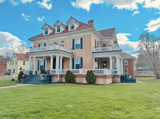 view of front of property featuring a balcony, covered porch, a front lawn, and brick siding