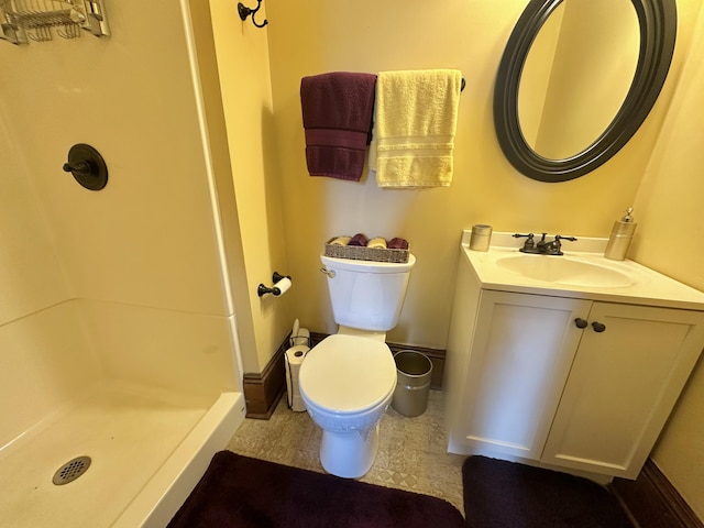 bathroom with a stall shower, baseboards, vanity, and toilet