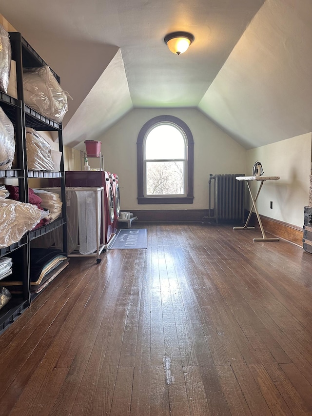 bonus room featuring baseboards, lofted ceiling, radiator heating unit, hardwood / wood-style floors, and independent washer and dryer