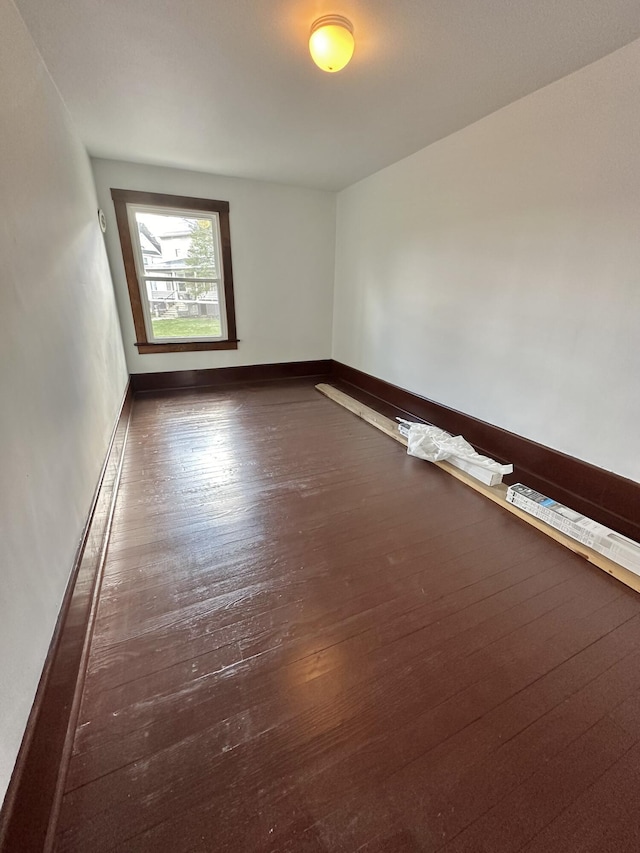 unfurnished room with baseboards and wood finished floors