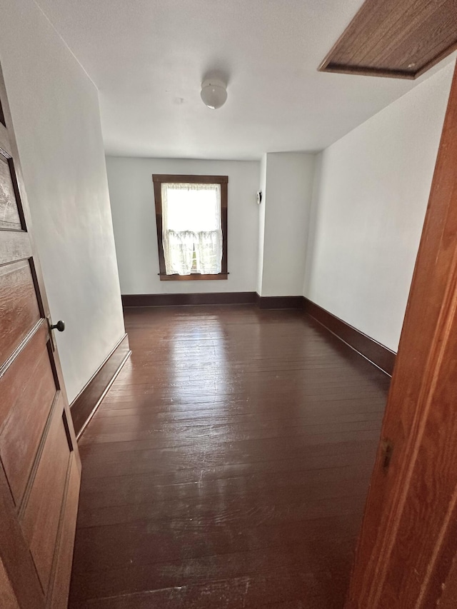 unfurnished room with dark wood-style flooring and baseboards