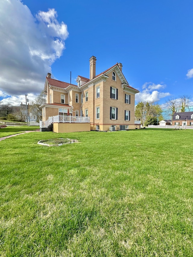 back of house featuring central AC, a yard, and a chimney