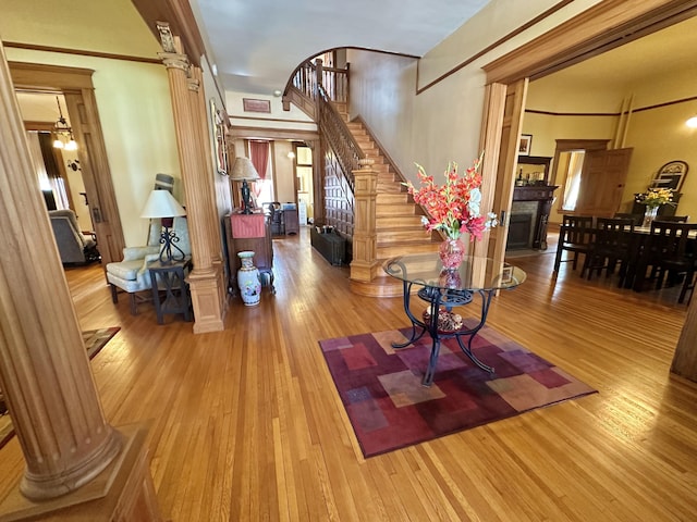 interior space with decorative columns, a fireplace, stairway, and wood finished floors