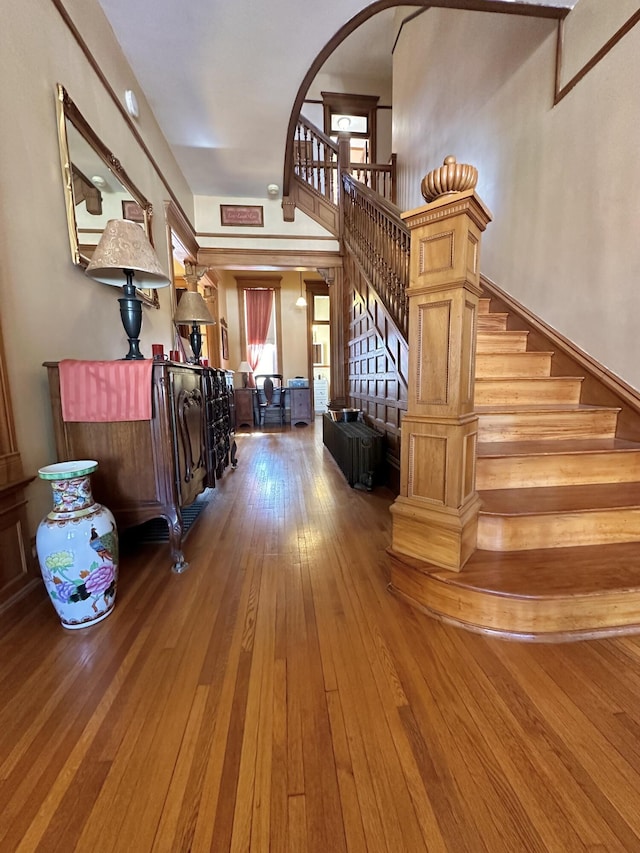 interior space with arched walkways, wood-type flooring, and stairs