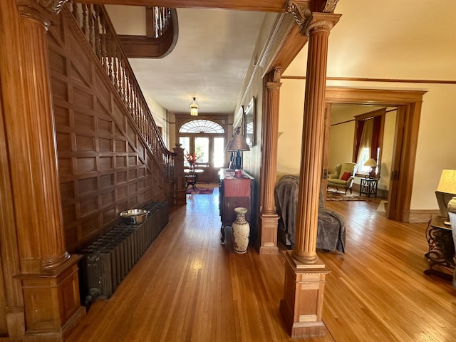 hall featuring stairway, wood-type flooring, and decorative columns