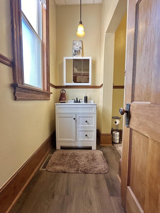 bathroom with vanity, wood finished floors, visible vents, and baseboards