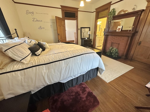 bedroom with ensuite bath, a fireplace, and wood finished floors