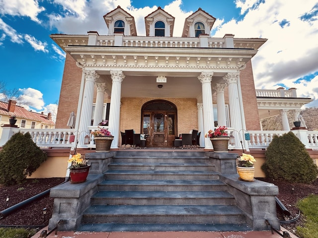 property entrance featuring french doors, a porch, and brick siding