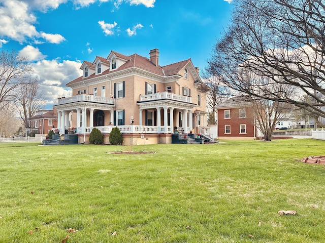 back of property with a yard, a chimney, and a balcony