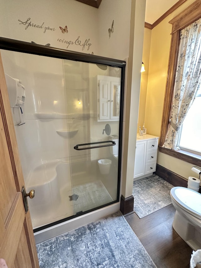 bathroom with toilet, a stall shower, vanity, wood finished floors, and baseboards