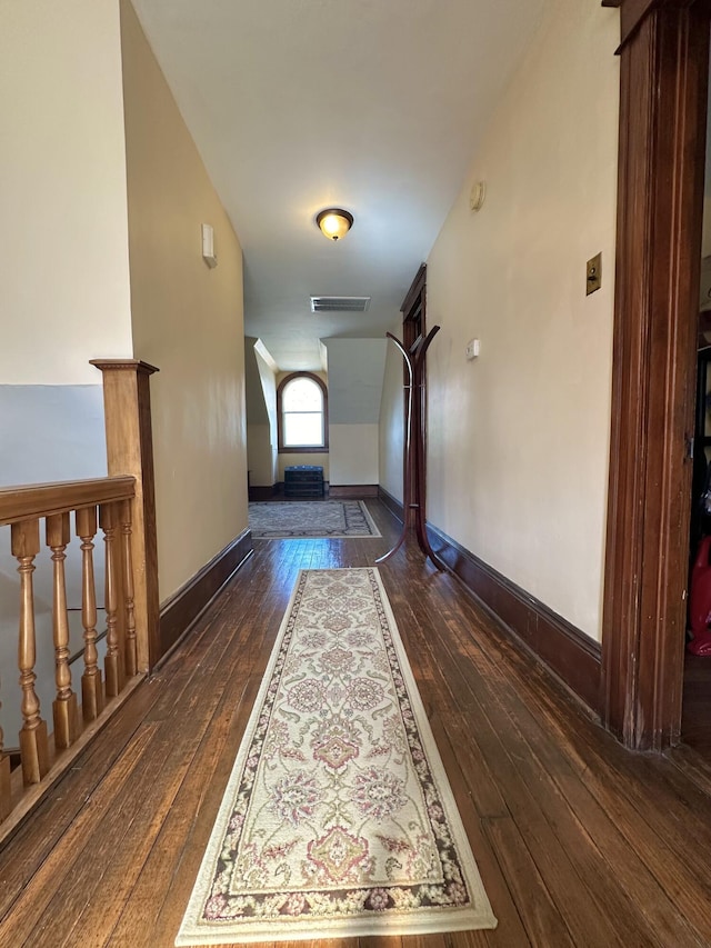 hallway with dark wood-type flooring, visible vents, and baseboards