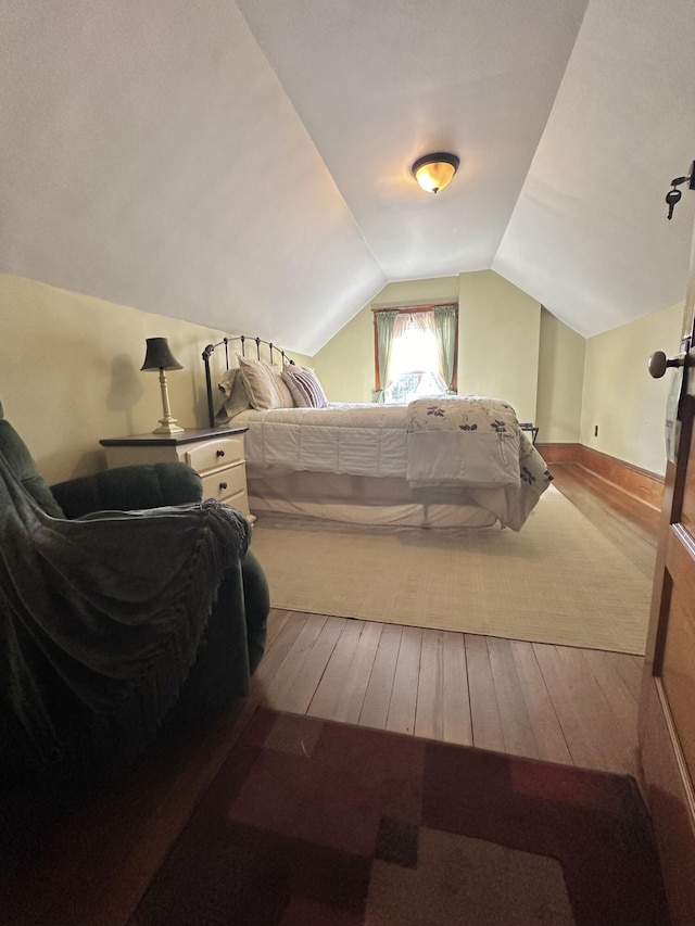 bedroom with lofted ceiling and wood-type flooring