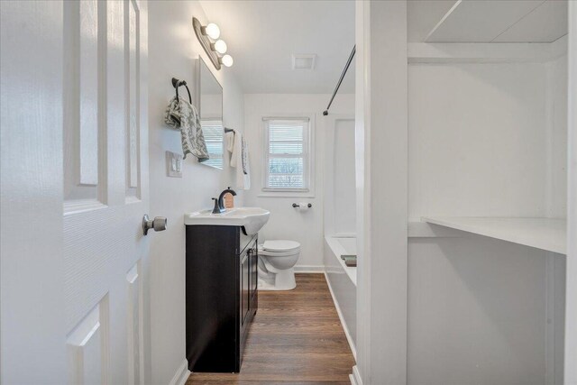 bathroom featuring vanity, wood finished floors, visible vents, bathing tub / shower combination, and toilet