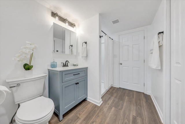 bathroom featuring visible vents, toilet, wood finished floors, baseboards, and vanity