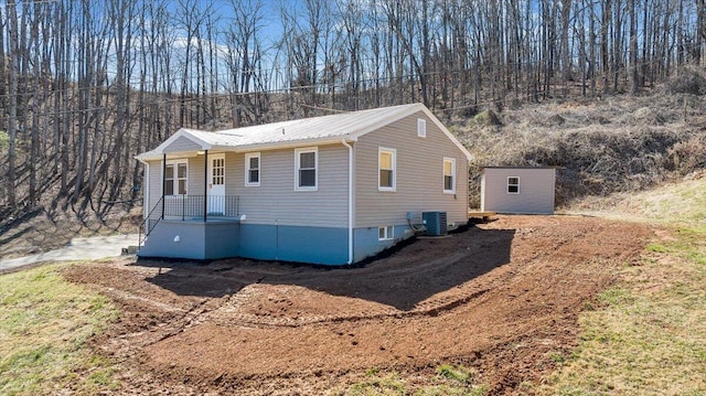 view of front of property featuring a porch, central air condition unit, and metal roof