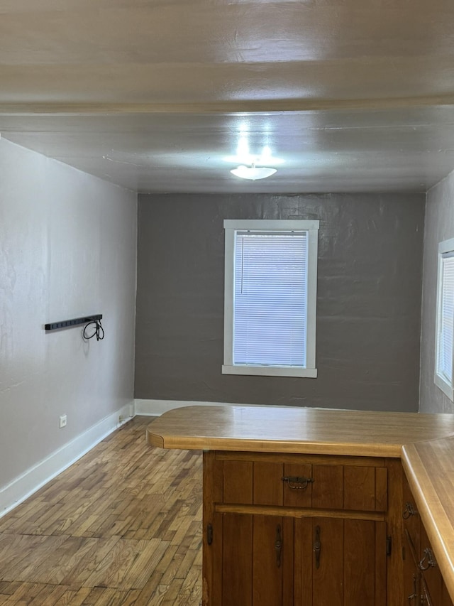 kitchen with brown cabinets, light countertops, light wood-type flooring, and baseboards