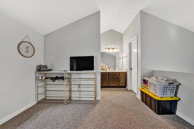 carpeted bedroom with baseboards, ensuite bath, and vaulted ceiling