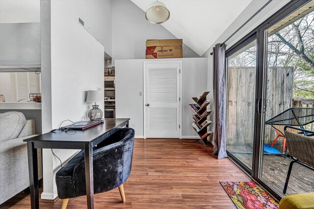 office featuring visible vents, baseboards, lofted ceiling, and wood finished floors