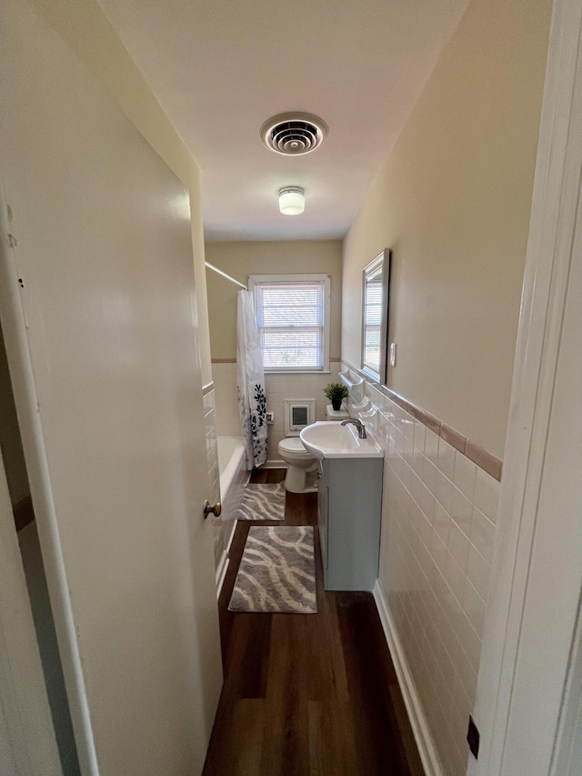 full bath featuring visible vents, a wainscoted wall, wood finished floors, vanity, and tile walls