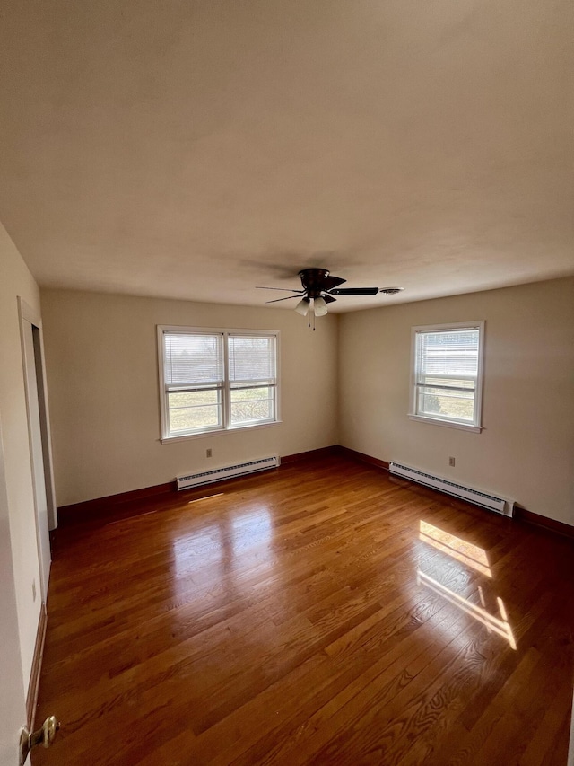 unfurnished room featuring a baseboard radiator, wood finished floors, and baseboards