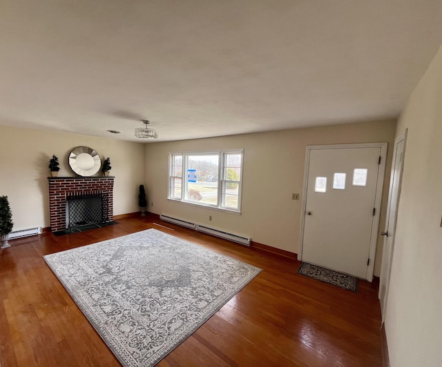 living area with a baseboard radiator, a fireplace, baseboard heating, and wood finished floors