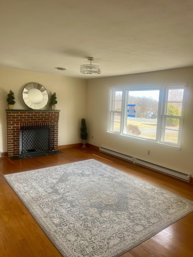 unfurnished living room featuring a baseboard radiator, a healthy amount of sunlight, a fireplace, and wood finished floors