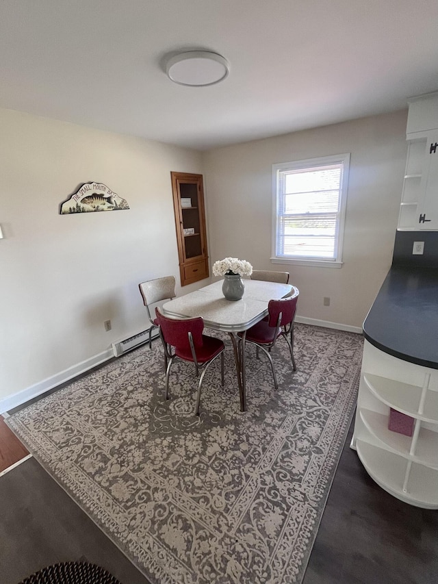 dining space featuring dark wood-style flooring, baseboard heating, and baseboards