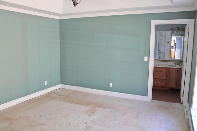 empty room with a sink, crown molding, light carpet, and baseboards