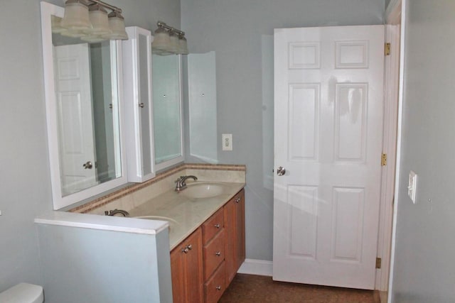 bathroom featuring double vanity, toilet, and a sink