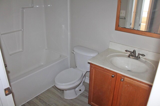 bathroom with toilet, shower / tub combination, wood finished floors, and vanity