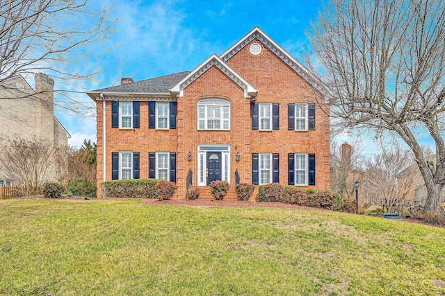 colonial home featuring a front yard, brick siding, and a chimney